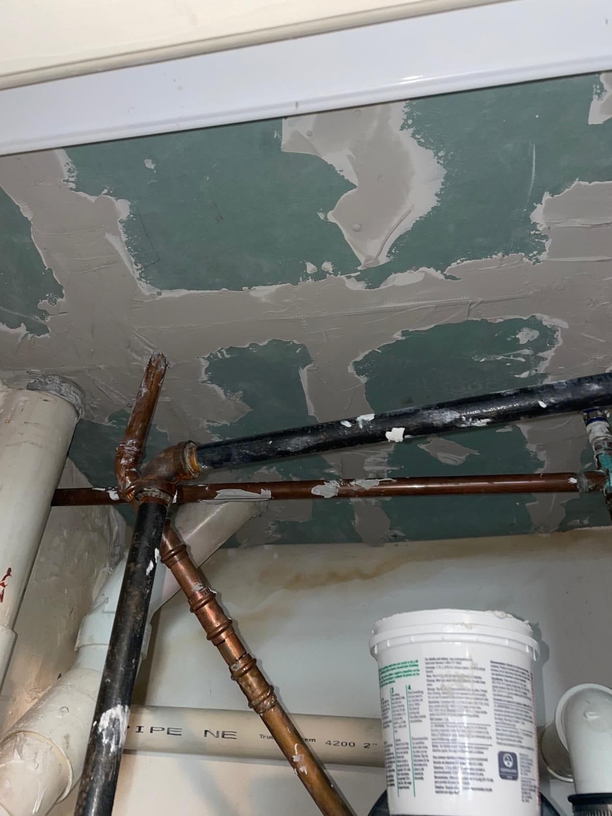 Drywall opened for copper pipe repair in a Boston ceiling