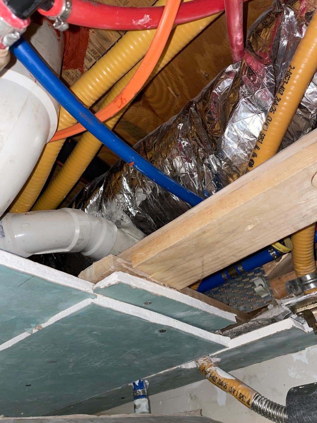 Open ceiling exposing pipes and insulation before repair in a Boston home