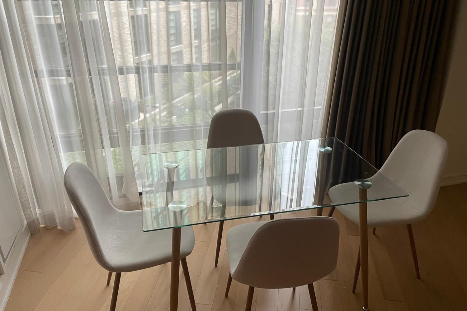 Glass dining table and upholstered chairs assembled by a Boston high-rise window